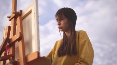 Kadın sanat ressam sarı montlu bir resim çizim.