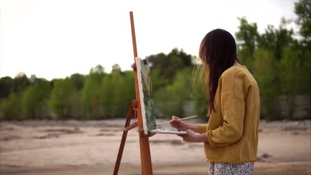 Plein air schilderen. Jonge kunstenaar werken op ezel buiten — Stockvideo