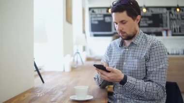 Rahat kıyafet kafede oturan adam. O onun smartphone kullanarak.