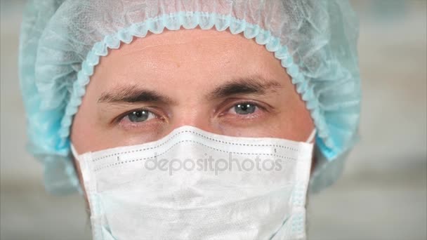 保護布マスクと彼の頭にキャップの若い男性医師の肖像画 — ストック動画