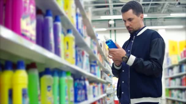 Hombre en la tienda leyendo una etiqueta sobre detergente — Vídeo de stock