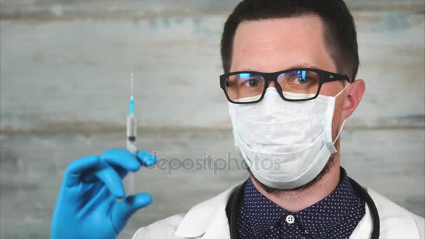 Male scientist or medic in white coat and protective mask holding syringe — Stock Video