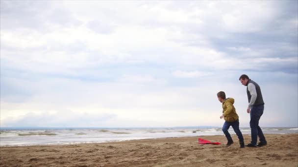 Lycklig familj. Pojke med sin far som spelar på stranden. Pojke lansera kite — Stockvideo