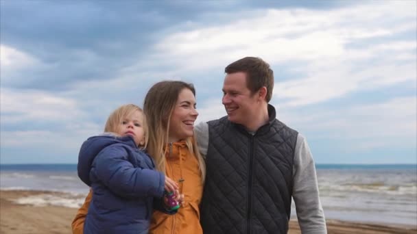 寒い日に海岸を歩き、小さな子供を持つ若い家族 — ストック動画