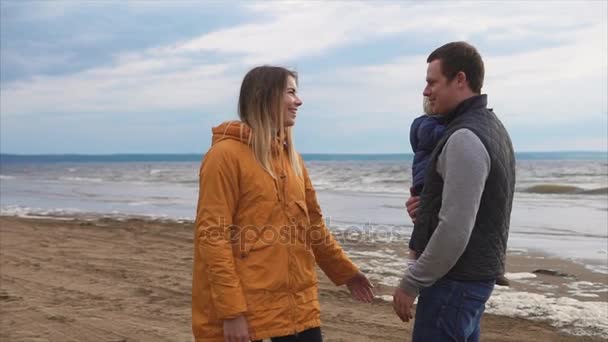 Joven familia muy unida con su pequeña hija junto al mar — Vídeos de Stock