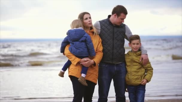 De man en zijn vrouw staan met de kinderen in de buurt van de zee en genieten van de dag — Stockvideo