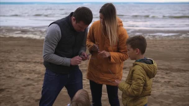 La famiglia giovane che accende luci di bengala su una riva di un fiume. Festeggiamenti familiari — Video Stock