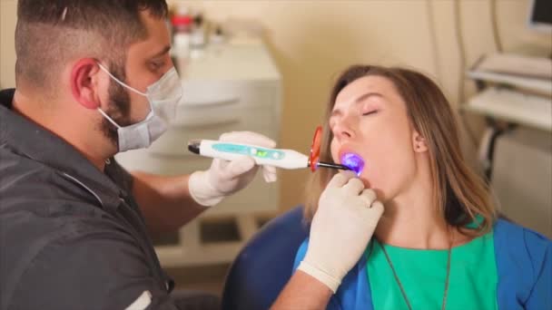 Dentista usando lámpara ultravioleta en los dientes de los pacientes . — Vídeos de Stock