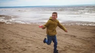 Mutlu bir çocuk hızlı elinde kum denize sıfır bir uçurtma ile çalışır
