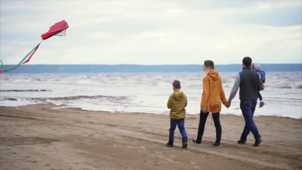 Joyeux famille marchant le long du rivage. Homme, femme, petit garçon et fille jouant — Video