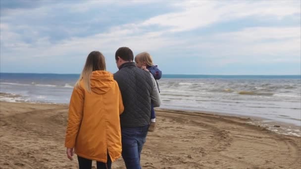 Caminata familiar en la orilla del océano. Hombre, mujer y niña — Vídeo de stock