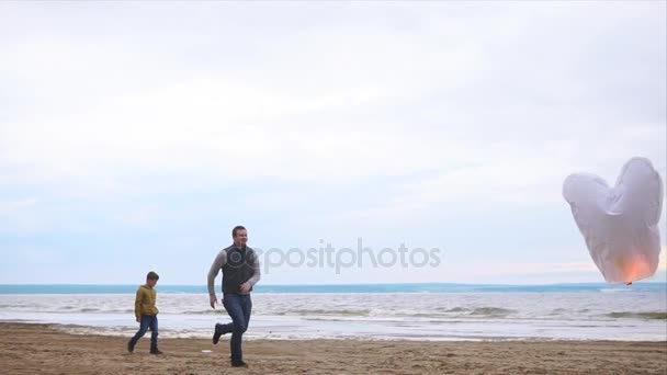 Eine freundliche Familie am Strand in der Nähe des Meeres, Papa rennt einer Papierlaterne hinterher — Stockvideo