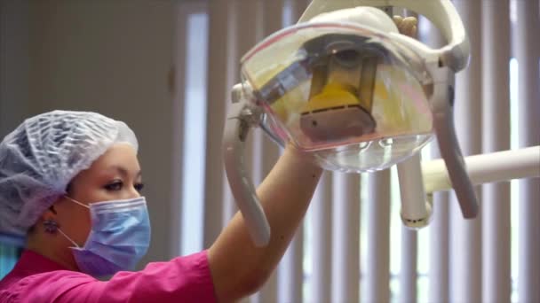 Médico fêmea em máscara protetora configurar a lâmpada médica — Vídeo de Stock