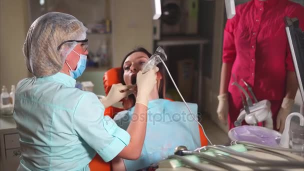 Orthodontist dokter vertelt de patiënt wat hij zal doen met tanden in de tandheelkunde — Stockvideo