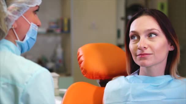 Gelukkig vrouwelijke patiënt in tandheelkundige kabinet. Gesprek tussen patiënt en tandarts — Stockvideo