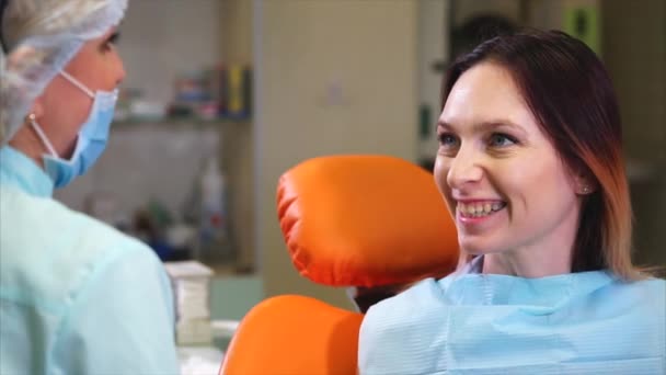 Пациентка стоматологической клиники спрашивает врача о том, как ухаживать за зубами — стоковое видео