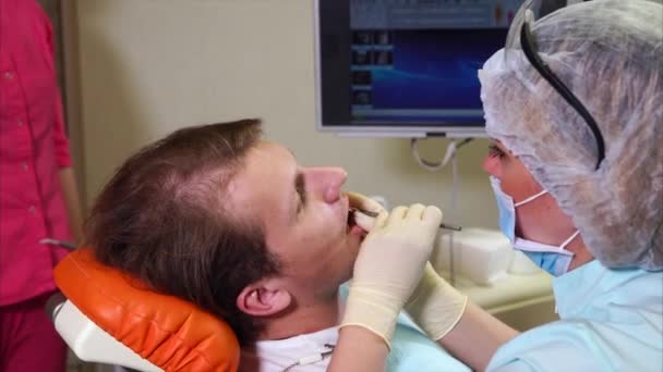 女性歯科医の男性患者のレントゲン写真を示す画面上でスキャンします。 — ストック動画