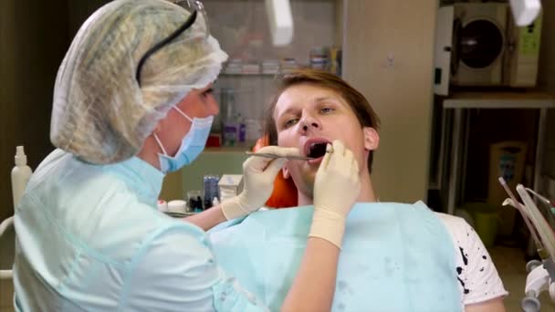 Врач-стоматолог проводит первичное обследование полости рта пациента — стоковое видео