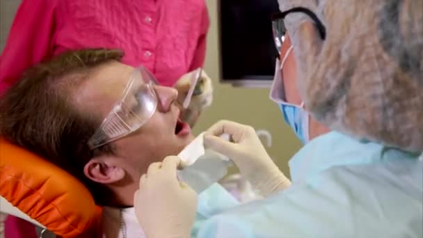 Мужчина, проходящий полировку зубов в зубной клинике — стоковое видео