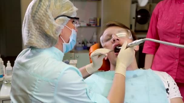 Orthodont зцілює зубів пацієнта, який прийшов на догляд за порожнини рота — стокове відео