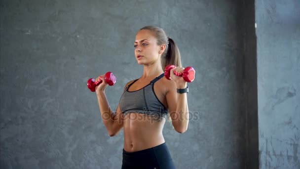 Junge Fitness-Frau beim Hantelheben im Fitnessstudio. Frau in Sportbekleidung — Stockvideo