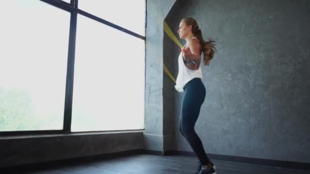 Egy vonzó és sportos lány jumping kötelet, részt vesz a cardio gyakorlatokat — Stock videók