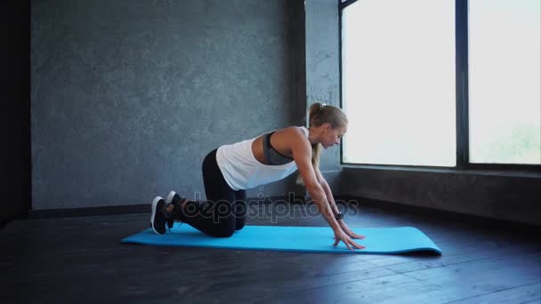 Junge Fitness-Frau beim Dehnen der Beine. Szene in der Sporthalle. Frau in Sportbekleidung — Stockvideo