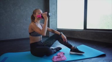 Mat spor ve egzersizler sonra dinlenme üzerinde oturan güzel uygun kadın.