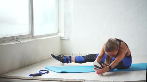 Mujer joven se dedica a la costura de piernas después de un entrenamiento físico activo — Vídeos de Stock