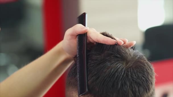 Detailní záběr záběr rukou kadeřníků, kteří zastřihne vlasy člověka v holičství — Stock video