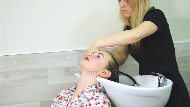 Kadeřnický salon. Žena zákazníka získávání vlasy umýt šamponem v salonu krásy — Stock video