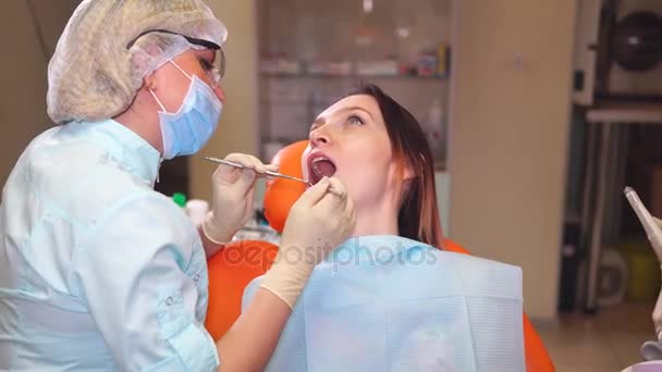 Стоматолог закінчує перевірку зубів молодої жінки — стокове відео