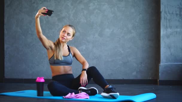 Uma mulher de esportes tira fotos no telefone depois de um treino em um clube de fitness — Vídeo de Stock