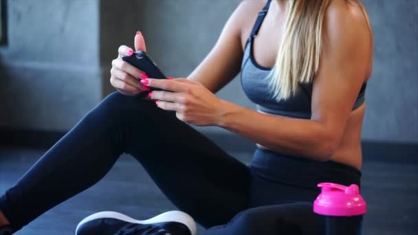 Bir telefon elinde tutan bir kadın sportif ve tabaklanmış vücut çekim — Stok video