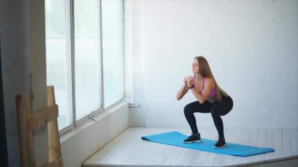 Bonita y atlética mujer hace sentadillas profundas para fortalecer las nalgas en el gimnasio — Vídeos de Stock