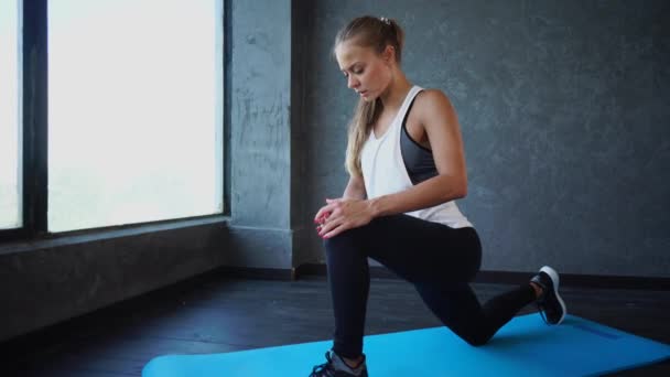 Молодая женщина, занимающаяся растяжением сухожилия на коврике для йоги в фитнес-клубе — стоковое видео