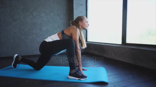Uitrekken. Mooie jonge vrouw doet benen strekken in de fitness-studio — Stockvideo