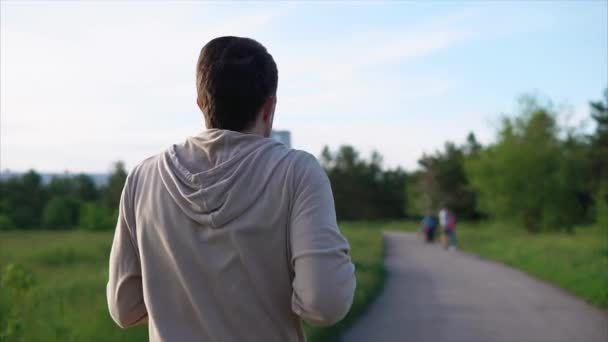 Dospělý muž běží sluchátka v parku, sportu se součástí jeho života — Stock video