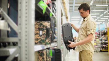 bir bavul bir tatil gezisi için yetişkin adam seçer, bir alışveriş merkezinde duruyor