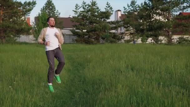 Atletische man doet een actieve training op het gebied van het park van de stad, hij springt — Stockvideo