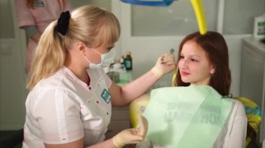 Dişçi genç hastayla konuşuyor. Genç kız uzman diş hekimi.
