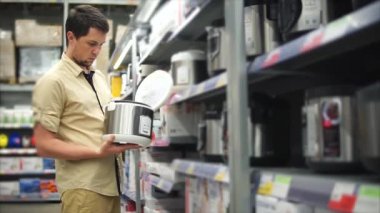 Alışveriş merkezinde erkek müşteri. Tek adam multicooker kendisi için seçme.