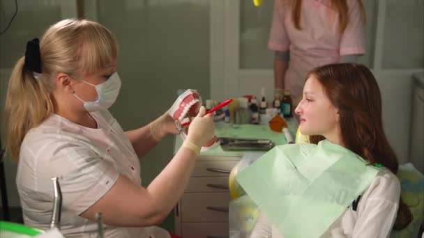 Doctor of the dental clinic shows the teenager how to properly brush his teeth — Stock Video