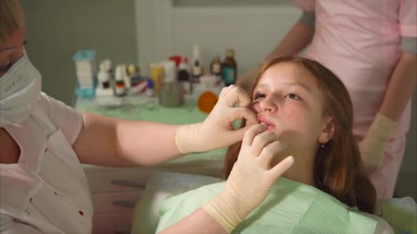 Стоматолог в латексных перчатках скрежещет зубы у подростка металлическим инструментом — стоковое видео