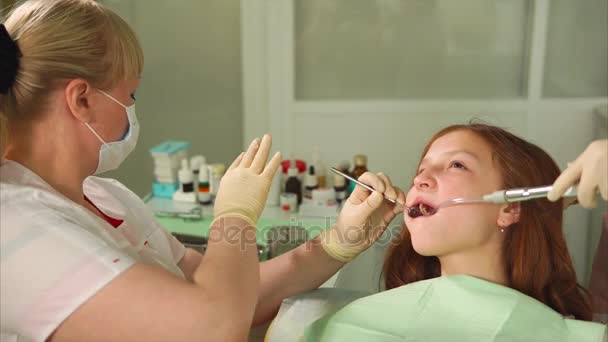Lekarz leczy zęby, Dziewczyna, Kobieta usuwa próchnicę wiertła — Wideo stockowe