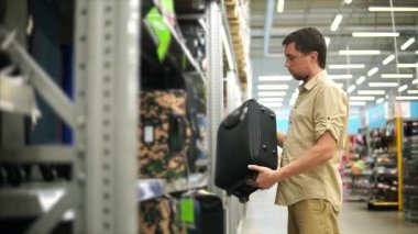 Erkek müşteri bavul seyahat için seçme. Elinde götürdüğünü