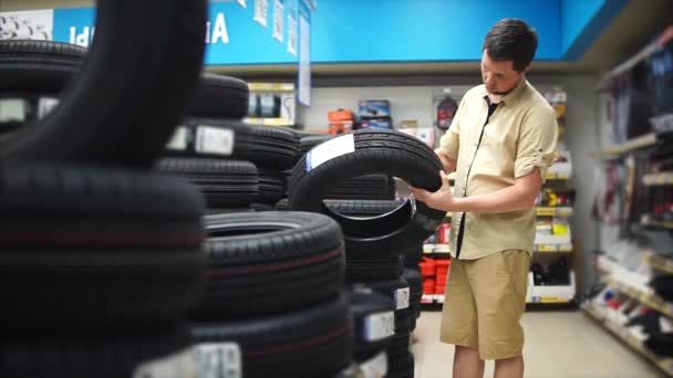 The car enthusiast choosing tires in the mall for his car. Man looking carefully — Stock Video