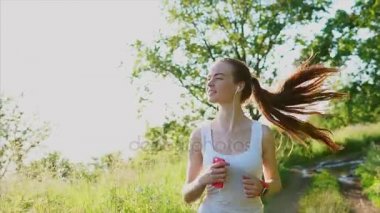 Doğa üzerinde koşu genç mutlu gülümseyen kadın. O müzik dinle.