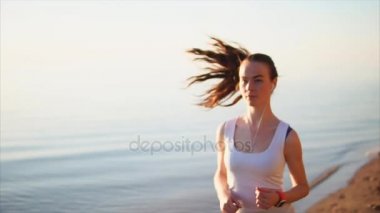 Denize yakın kum plajı üzerinde çalışan mutlu gülümseyen spor kadın.
