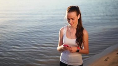 Onun smartphone kullanarak arkadaşları ile sohbet kum plajı üzerinde yürüyen kadın.
